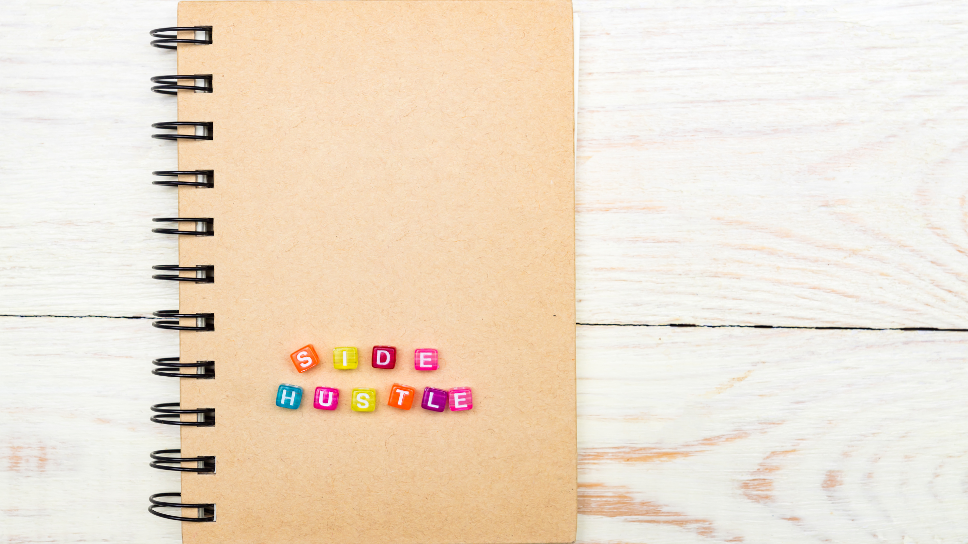 notepad with side hustle spelled out using colorful blocks on front cover